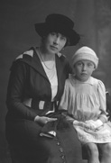 Mother seated with daughter.#