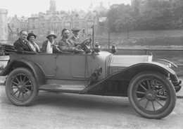 Scottish Home Rule Group outside the Palace Hotel, seated in a vintage car with Inverness Castle and Castle Tolmie buildings in background, demolished in 1959. Badge on front of the vehicle, RMC, possibly stands for Renault Motor Company. (Scot Auto Ass. Glasgow written on envelope?)*