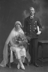 Married couple, he wearing uniform of the merchant marine, she in 1920s style wedding dress.#