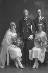 Married couple, he wearing uniform of the merchant marine, she in 1920s style wedding dress. With best man and bridesmaid.#