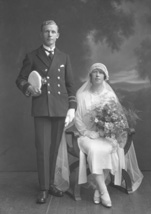 Married couple, he wearing uniform of the merchant marine, she in 1920s style wedding dress.#