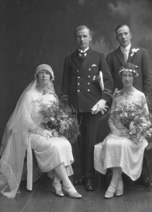 Married couple, he wearing uniform of the merchant marine, she in 1920s style wedding dress. With best man and bridesmaid.#