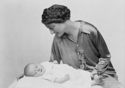 Mother with braids in hair looking over new baby.#