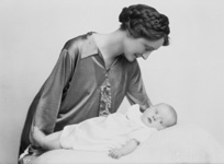 Mother with braids in hair looking over new baby.#