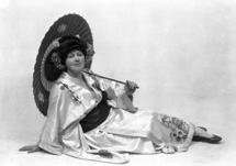 Carrie M. Cruickshank as Mimosa in the November 1927 production of 'The Geisha,' the story of a Japanese tea-house performed by the Northern Amateur Operatic Society. In the advert it was noted that prices would be increased for this attraction due to the lavish expense of the production (over ?200), in aid of the Queen Victoria Jubilee Institute for Nurses. A review noted that 'Miss Cruickshank has a beautiful voice, and went through the delicate Mimosa's ordeals of being sold and of selling with a sure finish.' #