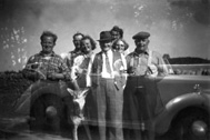Double exposure of group of people standing and people sitting in a car. #