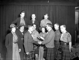 Scout ceremony. Dated c1930s and possibly taken in the since demolished Little Theatre at the top of Raining Stairs on Ardconnel Street, Inverness. The female adults are leaders of what was then called Wolf Cubs (under 11s) - the junior part of Scouting at that time. Man holding scroll appears in image H-0078. #