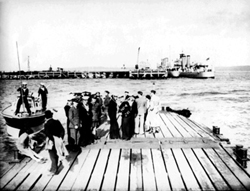 People at Invergordon queuing to take a trip by speedboat to the wreck of the HMS Natal c1932-1938. The small warship lying inboard of HMS Crusader is a 'Flower' Class Sloop of First World War  vintage.*