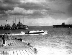 People at Invergordon queuing to take a trip by speedboat to the wreck of the HMS Natal c1932-1938. The H60 was a 'C' Class Destroyer built in 1932 and named HMS Crusader. (She was renamed HMCS Ottawa in 1938). At far right is the aircraft carrier HMS Courageous.*