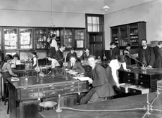 Inverness Royal Academy Science Laboratory, Academy, 1912. Between 1895-1980 the IRA was located in the Midmills building, currently the UHI-Inverness College (2013). The classroom scene was photographed at the time of the completion of the first extension to the Academy, running along Midmills Road opposite the side entrance to the Crown Church. The accommodation was shared in the early years with Inverness High School, when that school occupied the building which now houses the Crown School, only a short distance away. Accommodation included rooms for science and art, with a gymnasium and these are 'posed' publicity shots. This image was captioned Science Lab of Mr J.M. Lowson, MA BSc, Science Master, in the Highland Times, 2nd July 1914. (Courtesy Inverness Royal Academy Archive IRAA_053).