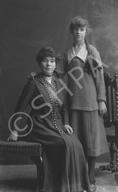 Elderly woman and young girl with long pleated ponytail, possibly mother and daughter.#.....