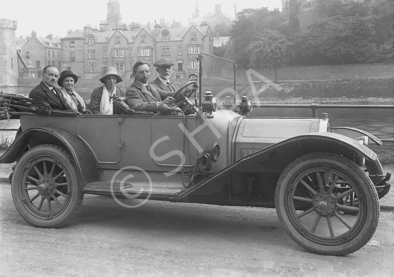 Scottish Home Rule Group outside the Palace Hotel, seated in a vintage car with Inverness Castle and Castle Tolmie buildings in background, demolished in 1959. Badge on front of the vehicle, RMC, possibly stands for Renault Motor Company. (Scot Auto Ass. Glasgow written on envelope?)*