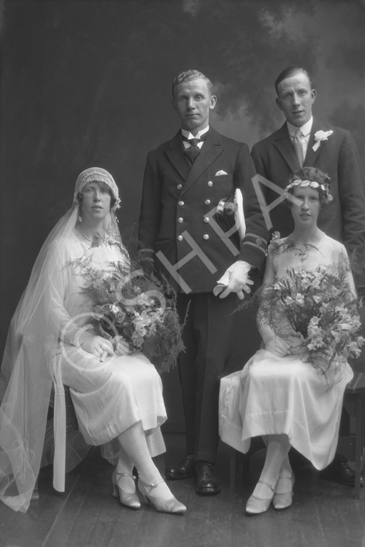 Married couple, he wearing uniform of the merchant marine, she in 1920s style wedding dress. With best man and bridesmaid.#