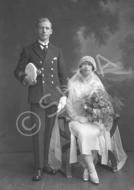 Married couple, he wearing uniform of the merchant marine, she in 1920s style wedding dress.#