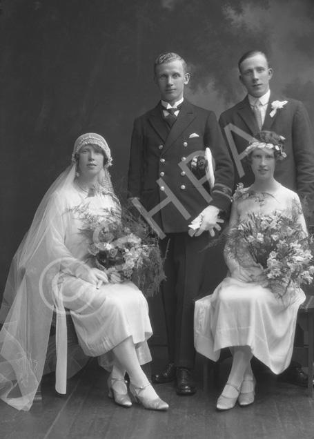 Married couple, he wearing uniform of the merchant marine, she in 1920s style wedding dress. With best man and bridesmaid.#