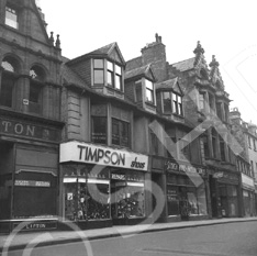 Timpson Shoes, located on the Inverness High Street. The building is no longer there, (the site is occupied by Shoe Zone), but the building on the left (Liptons Tea) is now the HSBC Bank. Image 26487a shows the Timpson store at the same location but with an earlier upper level facade. The elaborate building to the right is also gone, but the one on the extreme right of the photo still stands.*