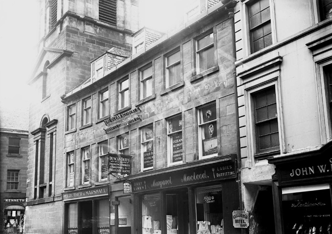 Church Street looking towards Bridge Street. The town clock steeple still exists but the buildings housing McGruther & Marshall and Margaret Macleod Ladies Outfitters are gone, including the alleyway leading to a back entrance of Gellion's Hotel, which is located on Bridge Street. The site is now occupied by Fife Country. The building on the far right is now McEwens of Perth. The clock steeple was erected beside the adjoining Court House and jail in 1791 and rises 45 metres. Gellions is the oldest pub in Inverness, established in 1841.*