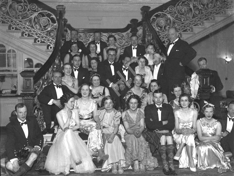 Group of people at a function, seated on the staircase in the Station Hotel, Inverness (now the Royal Highland Hotel). It is believed the stairs were used as the model for the Grand Staircase on the Titanic. # 