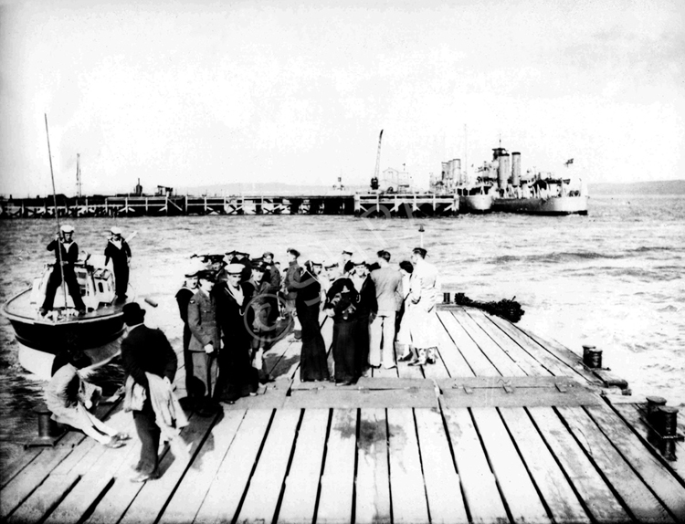 People at Invergordon queuing to take a trip by speedboat to the wreck of the HMS Natal c1932-1938. The small warship lying inboard of HMS Crusader is a 'Flower' Class Sloop of First World War  vintage.*