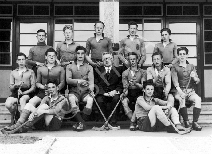 Shinty 1944-1945. Rear: T. Forrester, A. Cook,       A. MacDougall, S. Mackenzie, J. MacDougall. Middle: A. Wilson, R. MacKenzie, A. MacLeod,          Mr Graham, D. Campbell, B. Heatley, A. McDonald. Front: I. Mitchell, J. MacCartney. (Courtesy Inverness Royal Academy Archive IRAA_027).