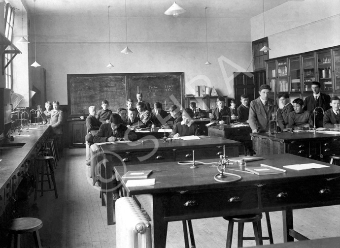 Inverness Royal Academy Science Laboratory, Room 18, High School, 1912. Between 1895-1980 the IRA was located in the Midmills building, currently the UHI-Inverness College (2013). The classroom scene was photographed at the time of the completion of the first extension to the Academy, running along Midmills Road opposite the side entrance to the Crown Church. The accommodation was shared in the early years with Inverness High School, when that school occupied the building which now houses the Crown School, only a short distance away. Accommodation included rooms for science and art, with a gymnasium and these are 'posed' publicity shots. This image was captioned Science Lab 2 in the Highland Times, 2nd July 1914. (Courtesy Inverness Royal Academy Archive IRAA_052).