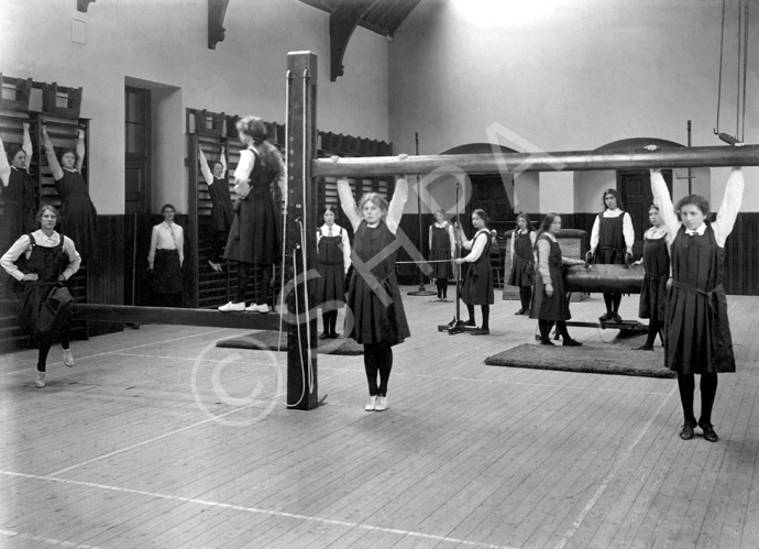 Inverness Royal Academy Gymnasium, 1912. Between 1895-1980 the IRA was located in the Midmills building, currently the UHI-Inverness College (2013). The classroom scene was photographed at the time of the completion of the first extension to the Academy, running along Midmills Road opposite the side entrance to the Crown Church. The accommodation was shared in the early years with Inverness High School, when that school occupied the building which now houses the Crown School, only a short distance away. Accommodation included rooms for science and art, with a gymnasium and these are 'posed' publicity shots. This image was captioned Gymnasium in the Highland Times, 2nd July 1914. (Courtesy Inverness Royal Academy Archive IRAA_057).